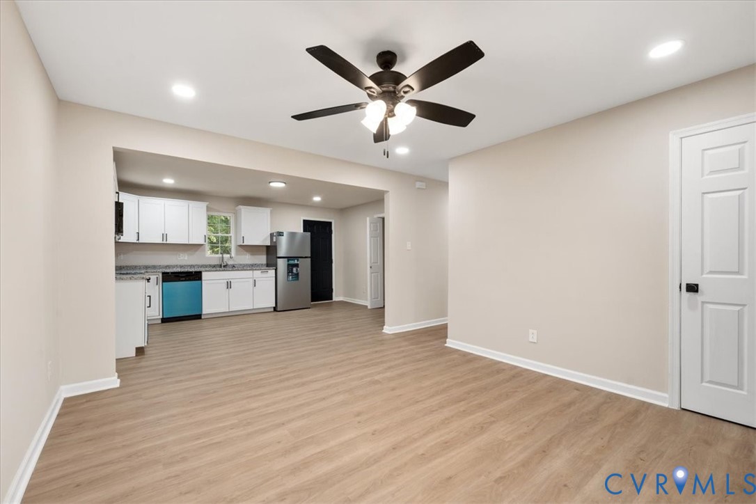 Kitchen featuring white shaker-style cabinetry, stone-surface countertops, wood-finish flooring, recessed lighting, and a dark-finish ceiling fan Kitchen featuring white shaker-style cabinetry, stone-surface countertops, wood-finish flooring, recessed lighting, and a dark-finish ceiling fan