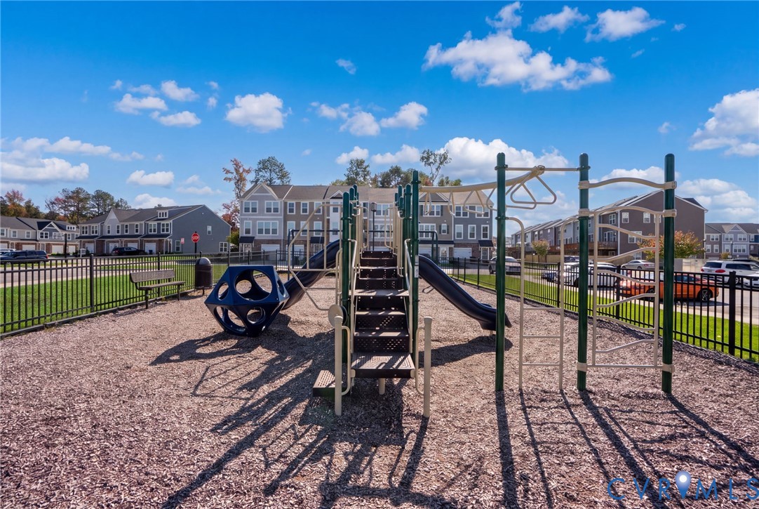 The fenced community playground features slides, climbing equipment, and nearby bench seating.