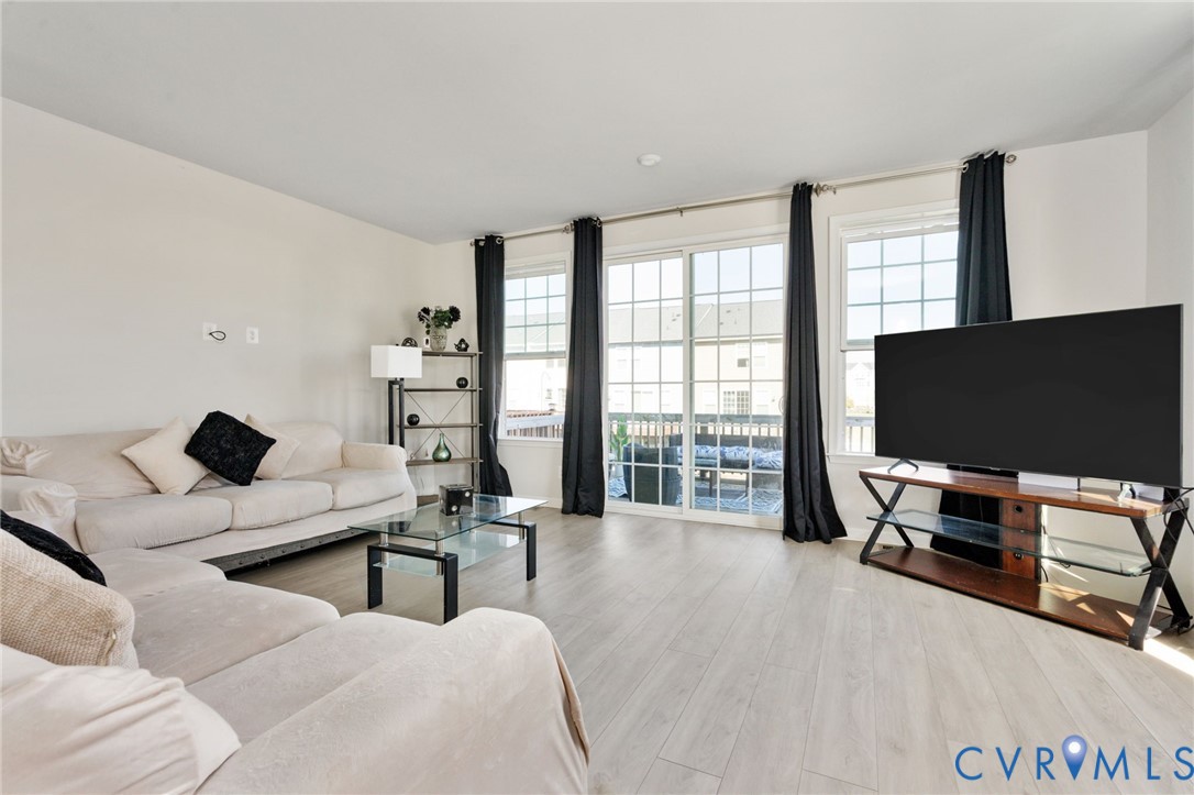 Living area featuring wood-finish flooring, sliding glass doors, and large dual-pane windows