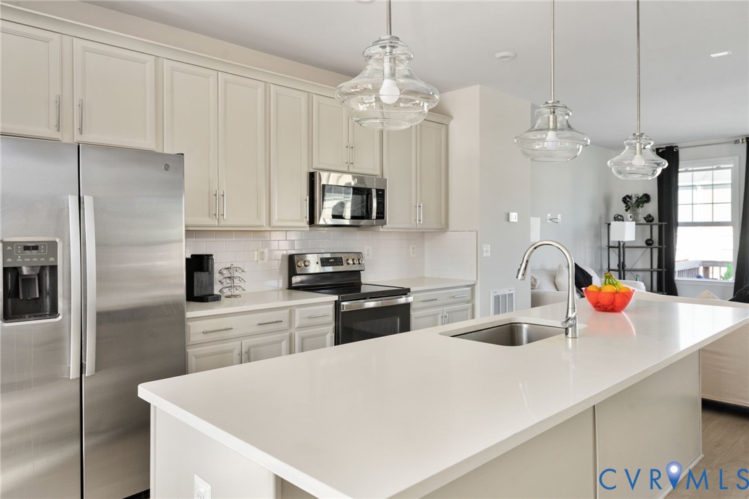 Generous counter space, ample cabinetry, and stainless steel GE appliances make this kitchen as functional as it is inviting, with a large island overlooking the living area.
