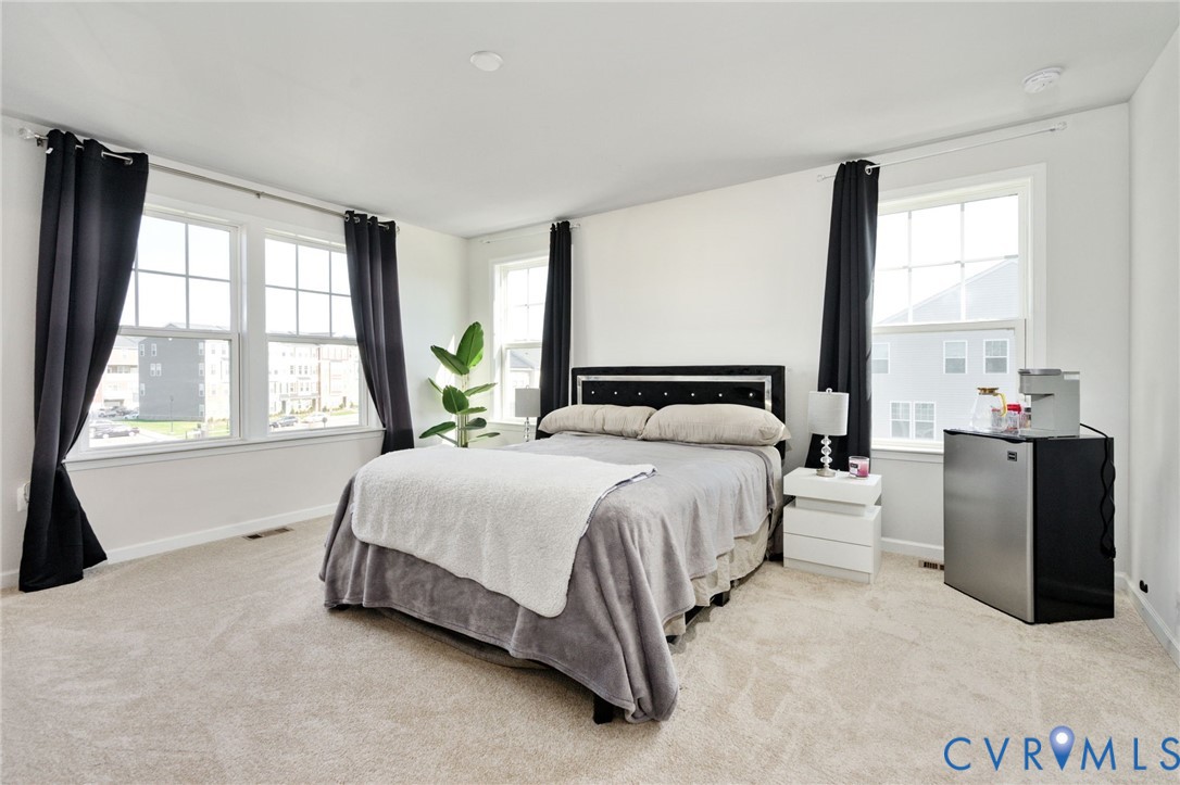 The spacious primary bedroom enjoys abundant natural light from windows on two sides, creating a bright and inviting retreat.