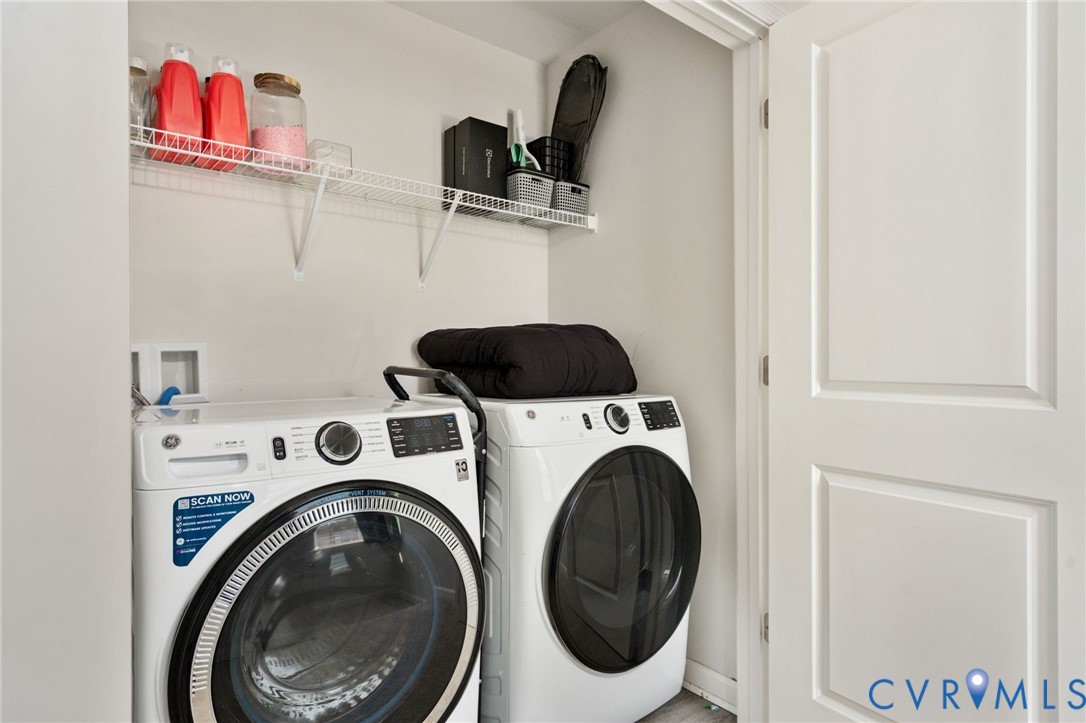 Conveniently located on the bedroom level, the laundry area accommodates a full-size GE washer and dryer with overhead shelving for storage.