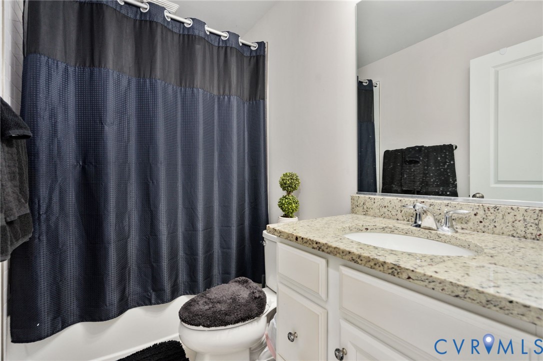 The full hall bath features a tub and shower combination, a spacious vanity countertop, and cabinet storage.