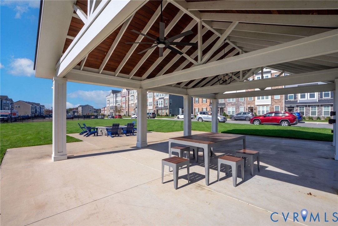 The covered community pavilion features shaded seating, ceiling fans, and views across the adjoining lawn and fire pit area.