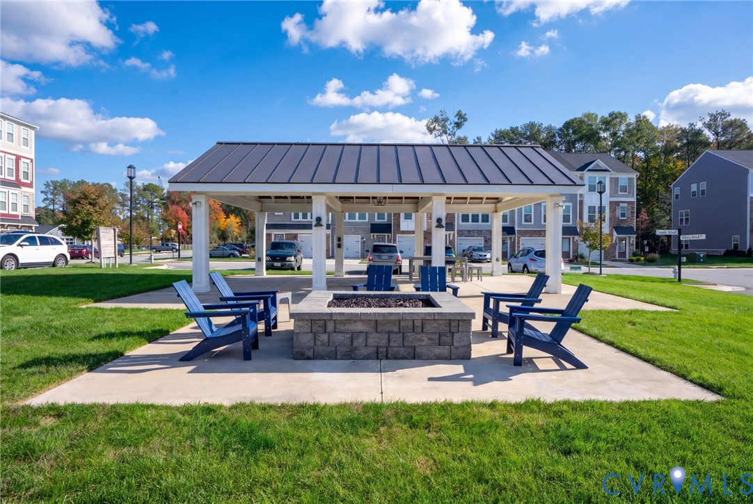 Gather around the community fire pit, featuring Adirondack seating beside the covered pavilion.
