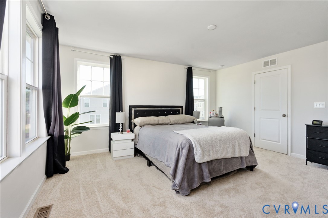 This alternate view showcases the primary bedrooms generous layout, neutral finishes, and room for additional furnishings.