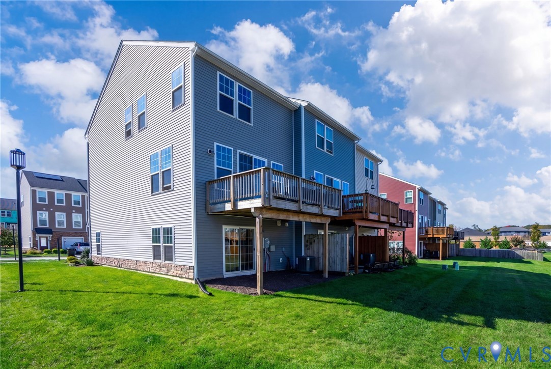 This rear view highlights the end-unit setting, additional side windows, elevated deck, and ground-level outdoor access.