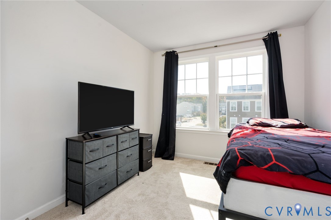 The second bedroom features two large windows, neutral walls, and comfortable carpeting, with flexibility for guests or a home office.