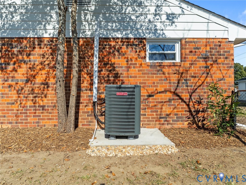 Exterior elevation featuring red brick masonry, white horizontal siding, a single-pane window, and a central HVAC unit mounted on a concrete slab