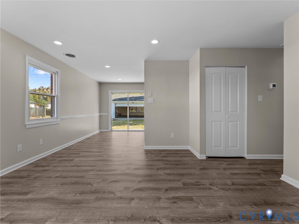 Interior space featuring wood-finish flooring, recessed lighting, double-panel closet doors, and sliding glass patio doors Interior space featuring wood-finish flooring, recessed lighting, double-panel closet doors, and sliding glass patio doors