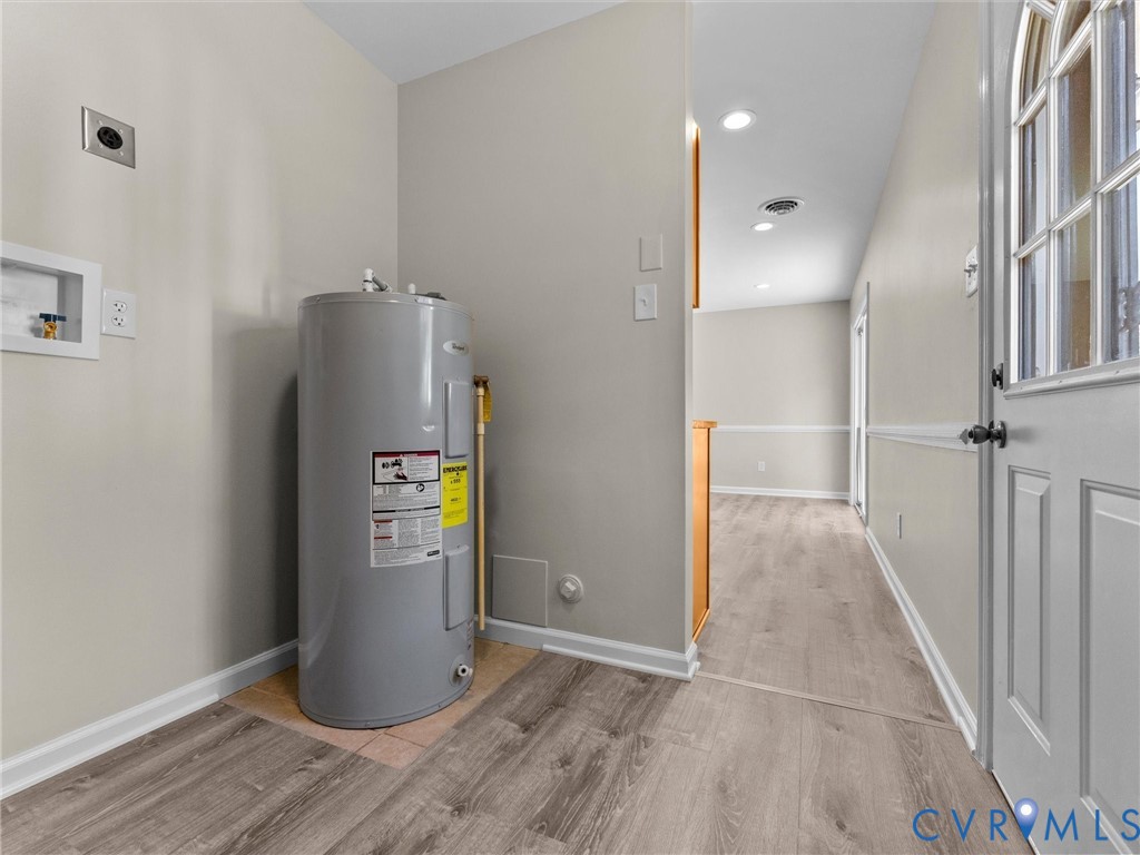 Utility area featuring water heater, laundry hookups, wood-finish flooring, recessed lighting, and exterior door with glass insert