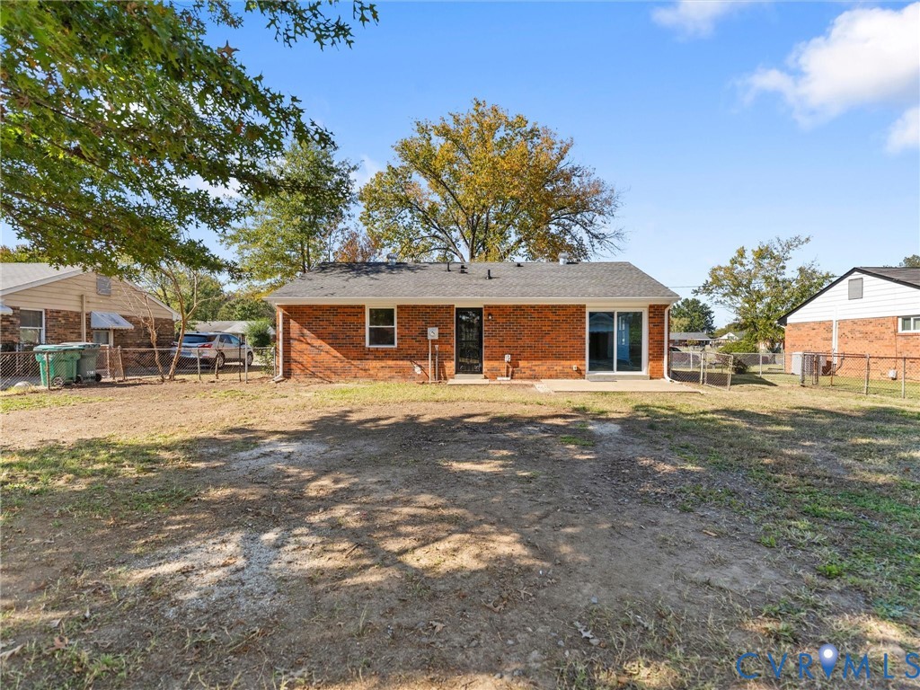 Full-brick exterior featuring a shingled roof, sliding glass doors, and a fenced-in rear yard with mature trees Full-brick exterior featuring a shingled roof, sliding glass doors, and a fenced-in rear yard with mature trees