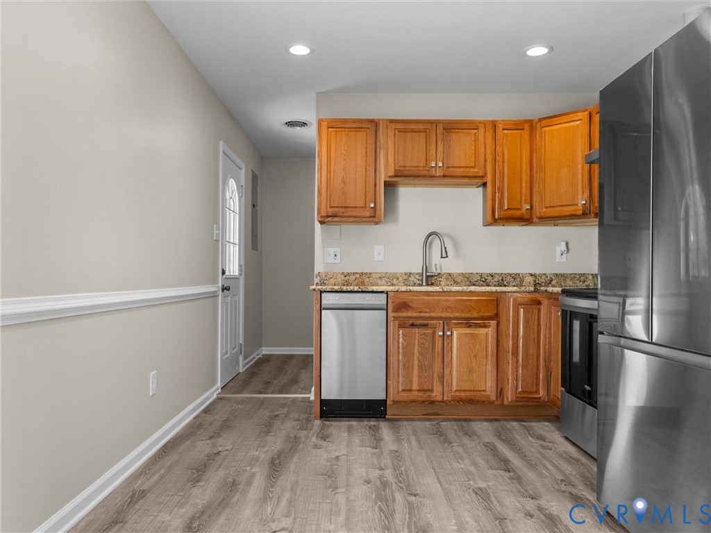 Kitchen featuring natural wood cabinetry, stone-surface countertops, stainless steel appliances, recessed lighting, and wood-finish flooring Kitchen featuring natural wood cabinetry, stone-surface countertops, stainless steel appliances, recessed lighting, and wood-finish flooring
