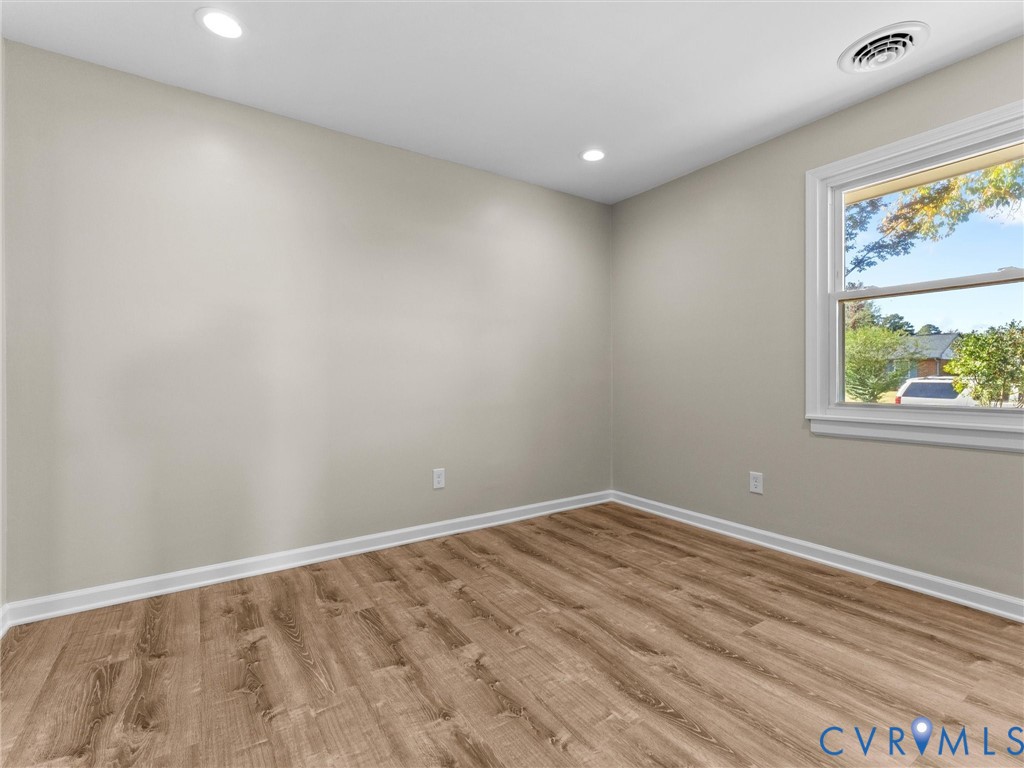 Interior room featuring wood-finish flooring, neutral wall paint, and recessed lighting