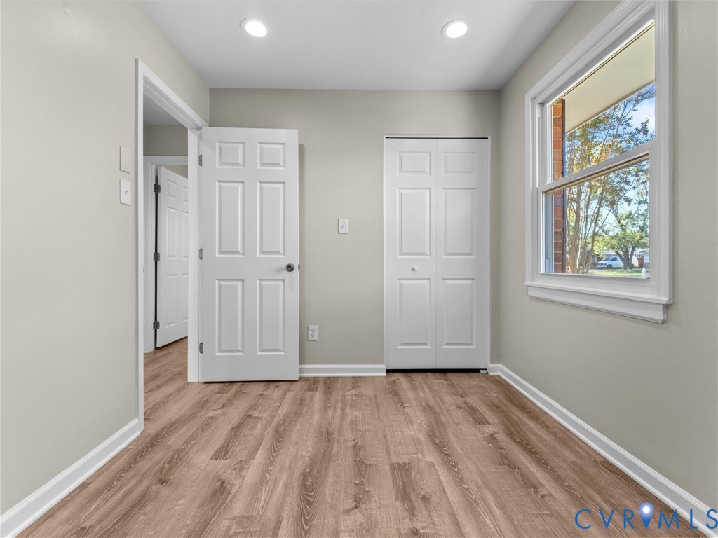 Room featuring wood-finish flooring, recessed lighting, and a dual-panel closet