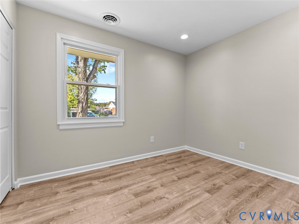 Neutral-toned interior room featuring wood-finish flooring, recessed lighting, and a double-pane window