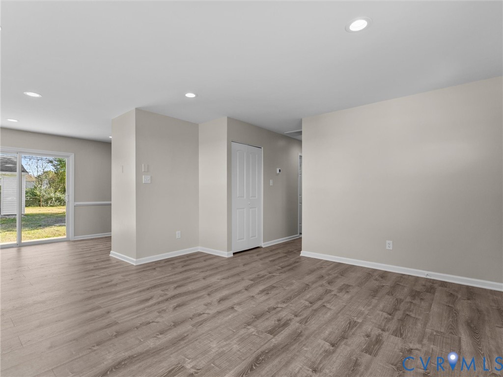 Neutral interior space featuring wood-finish flooring, recessed lighting, and a sliding glass door Neutral interior space featuring wood-finish flooring, recessed lighting, and a sliding glass door