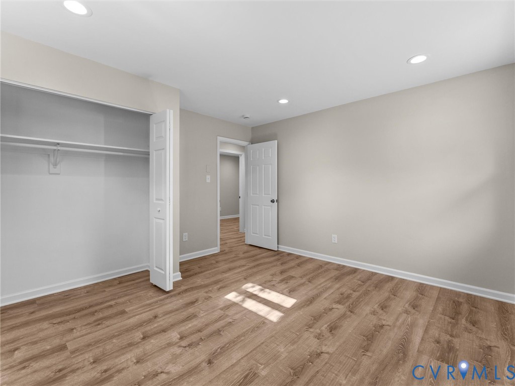 Neutral-toned interior featuring wood-finish flooring, recessed lighting, and a bi-fold closet door