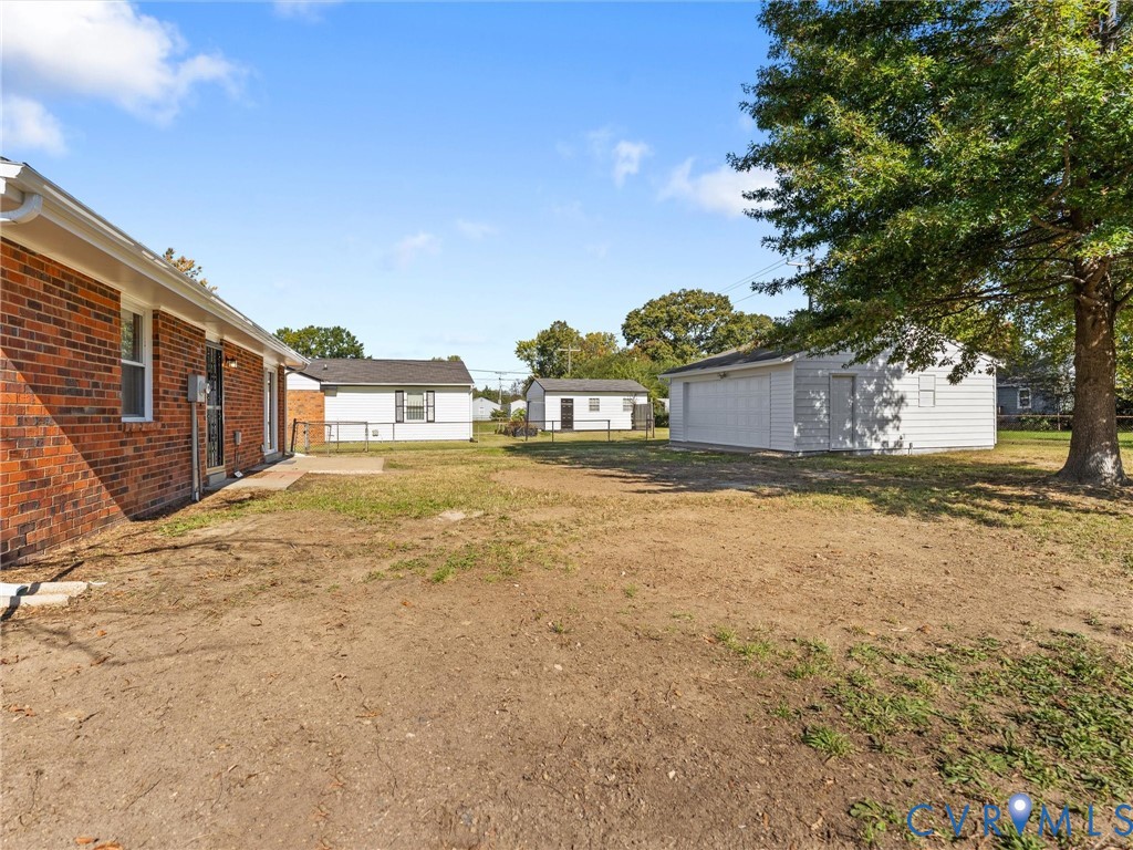 Red brick exterior, detached white garage, and expansive yard featuring mature trees