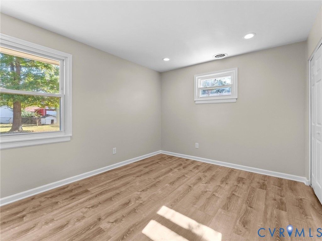 Neutral-toned interior room featuring wood-finish flooring, recessed lighting, and white paneled doors