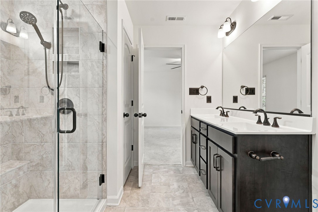 Walk-in shower with floor-to-ceiling tile, frameless glass enclosure, and built-in shelving