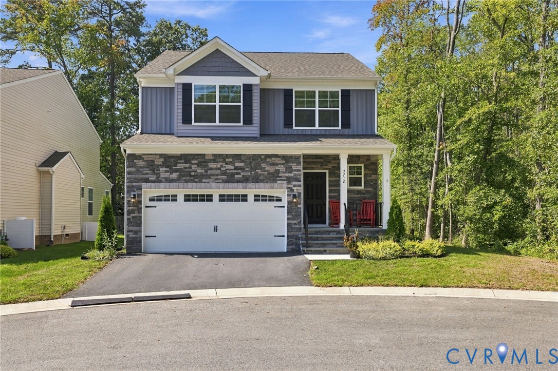 Two-story exterior featuring stone veneer siding, a front-facing gable roof, shuttered windows, and an attached two-car garage