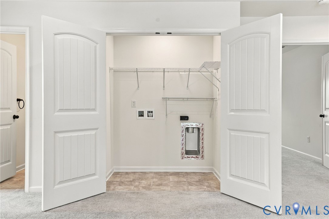 Laundry closet featuring dual-panel interior doors, vinyl tile flooring, wire shelving, and dedicated utility hookups