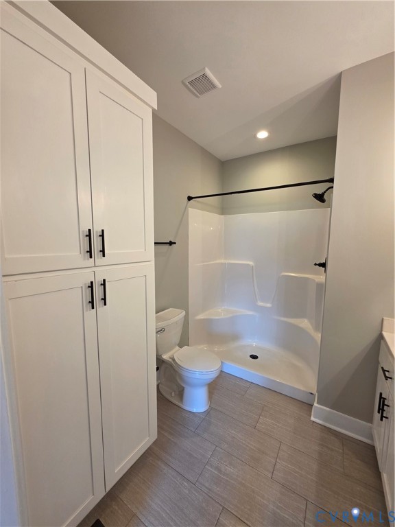 Floor-to-ceiling white cabinetry with matte black hardware, tile flooring, and a walk-in shower enclosure featuring matte black fixtures