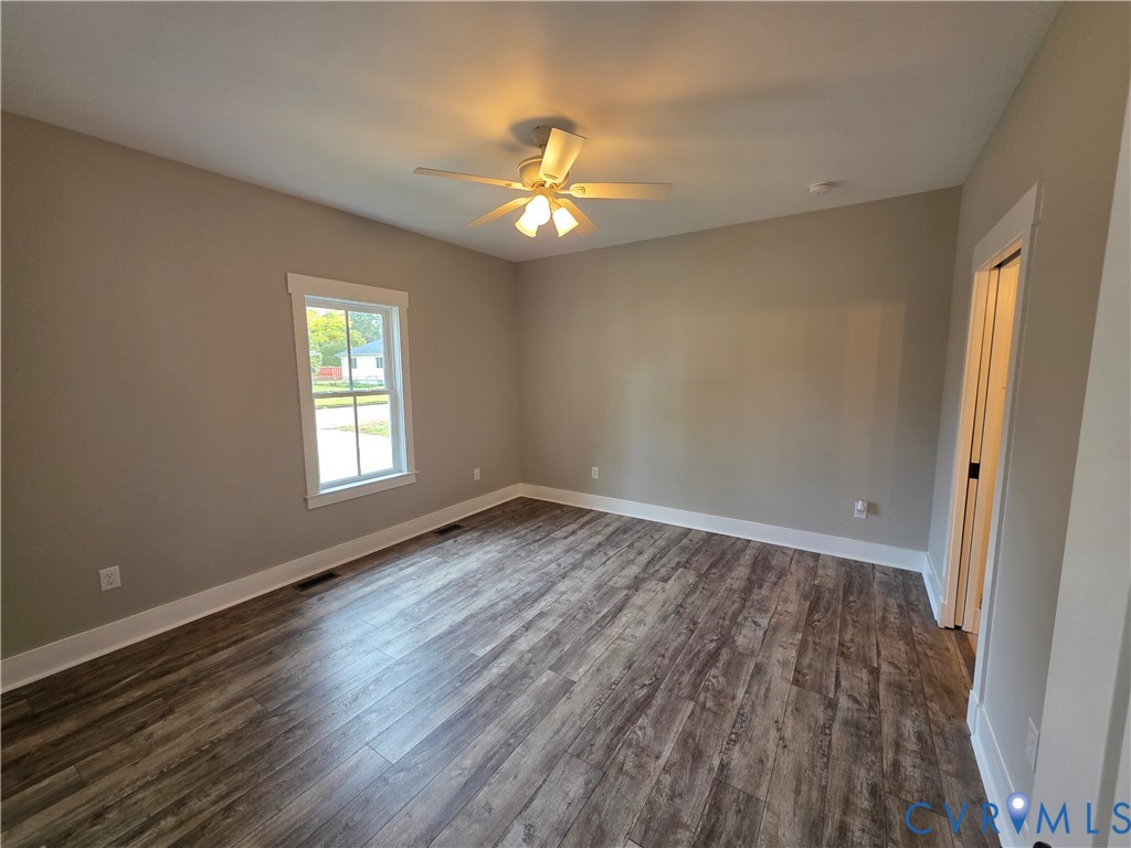 Room featuring wood-finish flooring, neutral wall paint, a single-window configuration, and a ceiling fan with integrated lighting