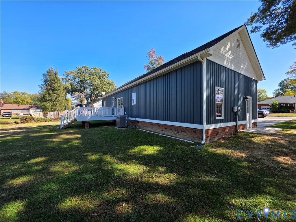 Exterior profile featuring vertical siding, a brick foundation, a white deck, and a peaked roofline