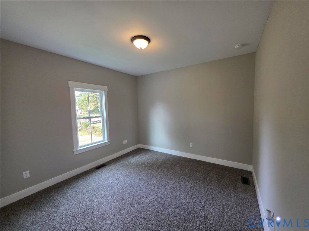 Neutral-toned walls, wall-to-wall carpeting, single-hung window with white casing, and flush-mount ceiling light fixture