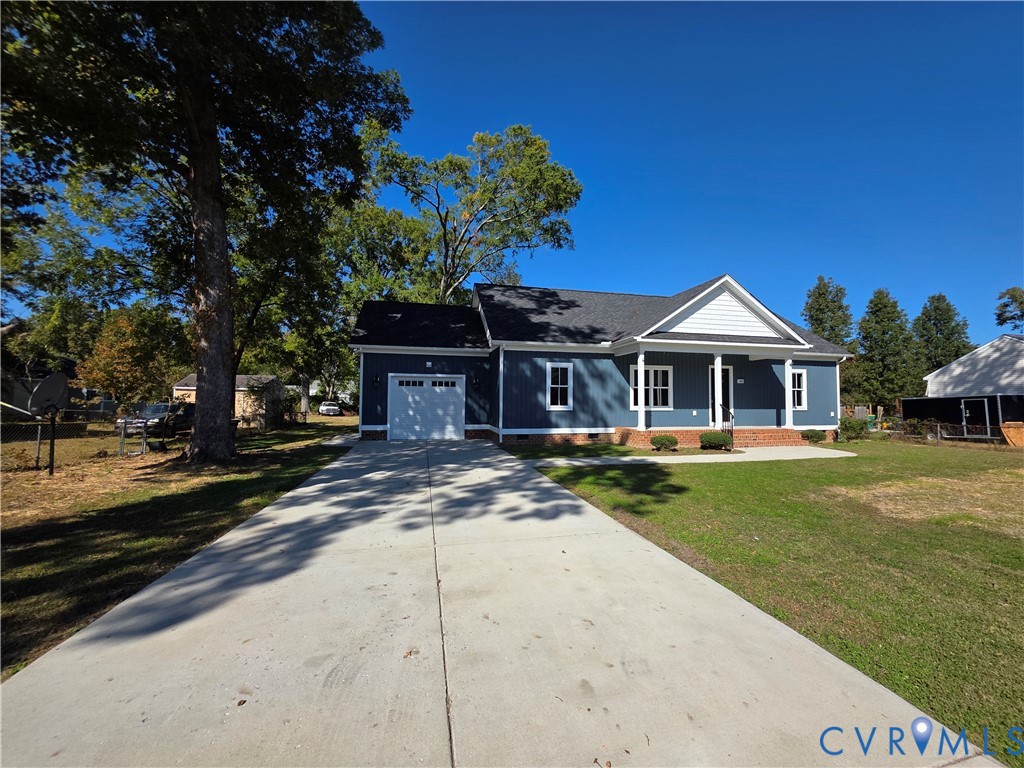 Single-story exterior featuring blue siding, a covered front porch with white columns, a shingled roof, and an attached garage with a concrete driveway Single-story exterior featuring blue siding, a covered front porch with white columns, a shingled roof, and an attached garage with a concrete driveway