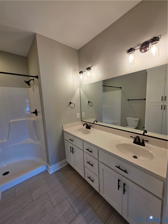 Dual-sink vanity with white cabinetry, integrated solid-surface countertop, matte black fixtures, full-width wall mirror, and porcelain tile flooring