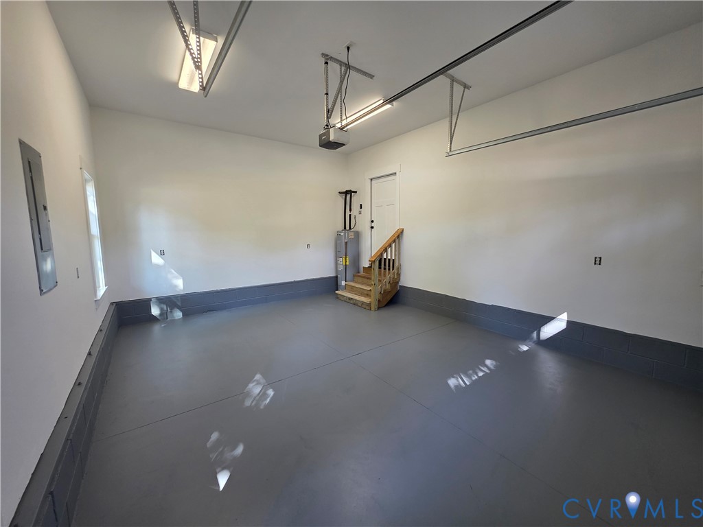 Finished garage featuring epoxy-coated flooring, painted masonry walls, overhead lighting fixtures, and built-in mechanical components