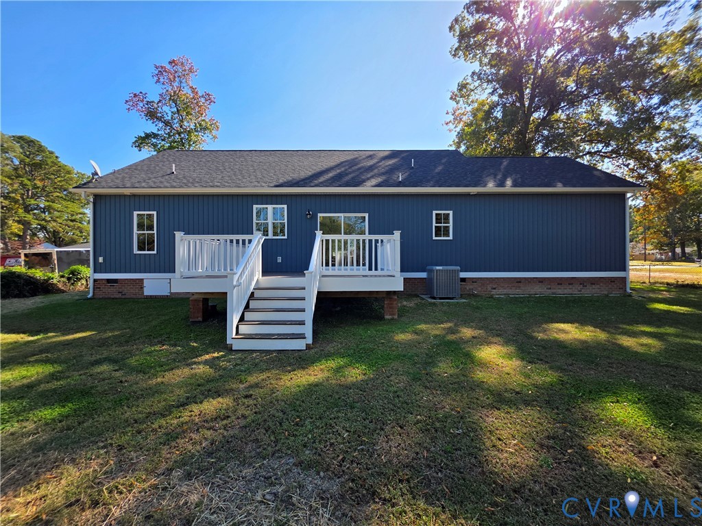 Exterior featuring blue vertical siding, a raised white deck with stairs, a brick foundation base, and a shingled roof Exterior featuring blue vertical siding, a raised white deck with stairs, a brick foundation base, and a shingled roof