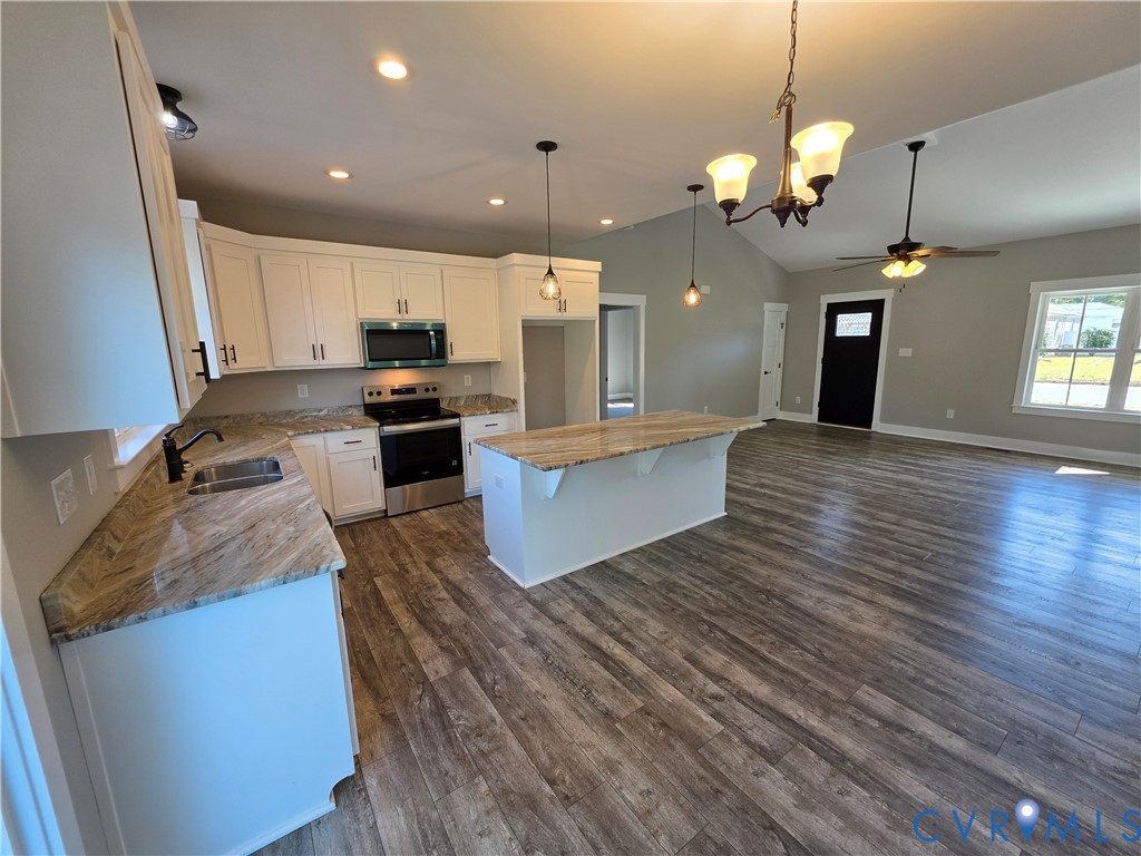 Kitchen featuring white cabinetry, stone-surface countertops, a center island, stainless steel appliances, and wood-finish flooring