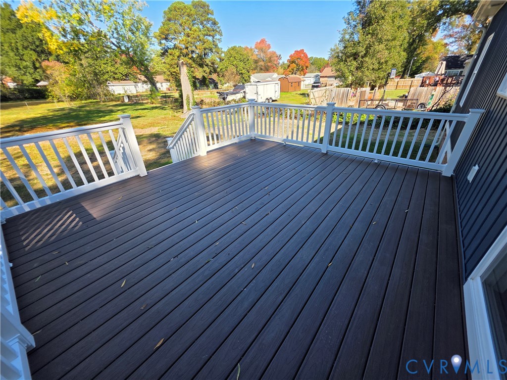 Elevated composite deck featuring white railings and staircase, dark-toned decking, and vertical exterior siding Elevated composite deck featuring white railings and staircase, dark-toned decking, and vertical exterior siding