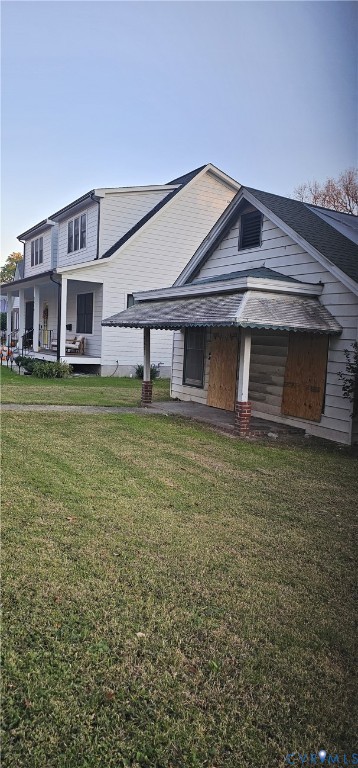 Exterior perspective featuring two-story and single-story structures with horizontal siding, a covered porch, brick column bases, and a pitched roofline