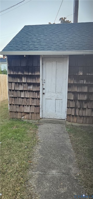 Detached structure featuring cedar shingle siding, a gable roof with asphalt shingles, and a painted wooden door