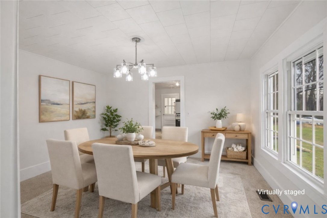 Room featuring a multi-light metal chandelier, paneled ceiling, and double-pane windows