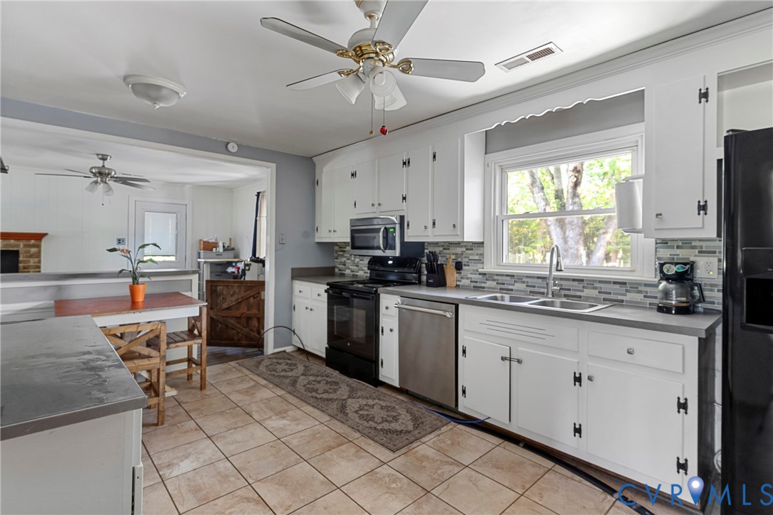 Kitchen featuring white cabinetry, stainless steel appliances, multi-toned tile backsplash, solid-surface countertops, and tile flooring Kitchen featuring white cabinetry, stainless steel appliances, multi-toned tile backsplash, solid-surface countertops, and tile flooring