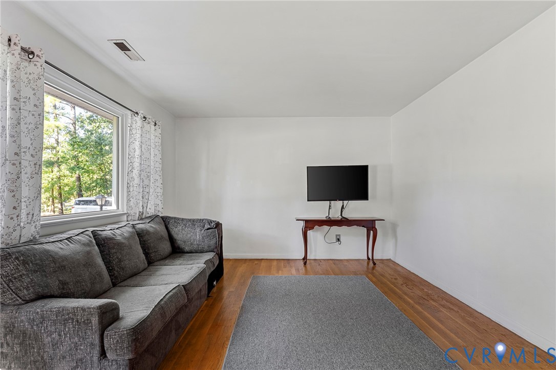 Living area featuring wood-finish flooring and a window with exterior exposure Living area featuring wood-finish flooring and a window with exterior exposure