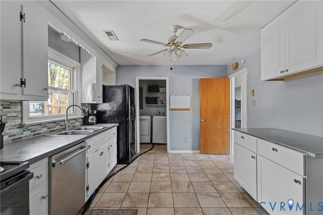 Kitchen featuring white cabinetry, tile flooring, stone-finish countertops, stainless steel dual-basin sink, and multi-colored mosaic backsplash Kitchen featuring white cabinetry, tile flooring, stone-finish countertops, stainless steel dual-basin sink, and multi-colored mosaic backsplash