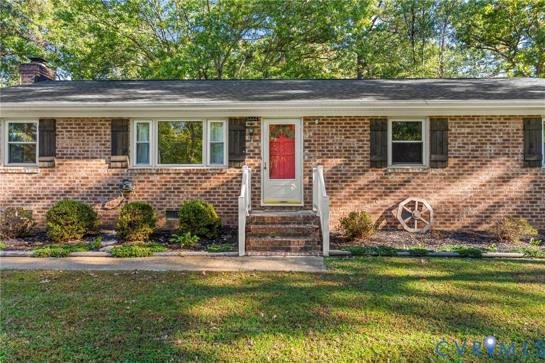 Brick exterior featuring decorative shutters, a covered entryway with white railings, and mature landscaping Brick exterior featuring decorative shutters, a covered entryway with white railings, and mature landscaping