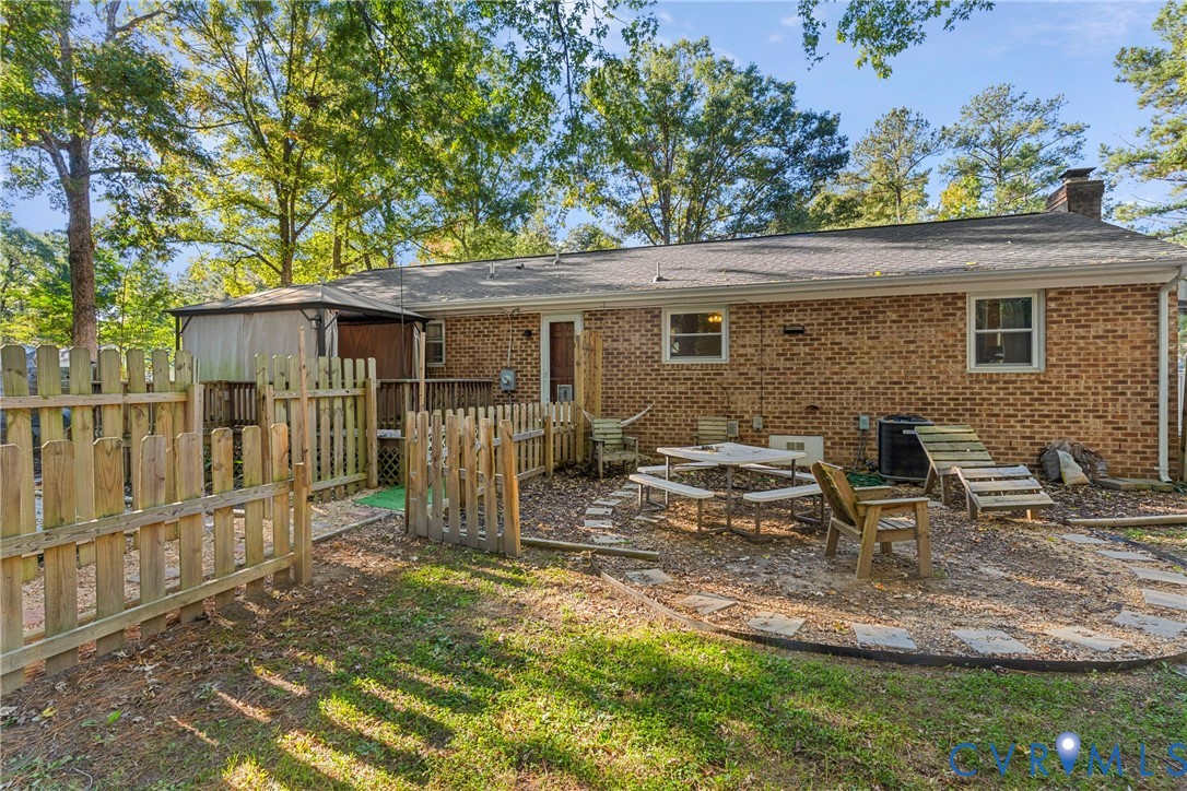 Exterior brick facade featuring a wood-style privacy fence, a wooden deck, and a multi-tiered outdoor hardscape area