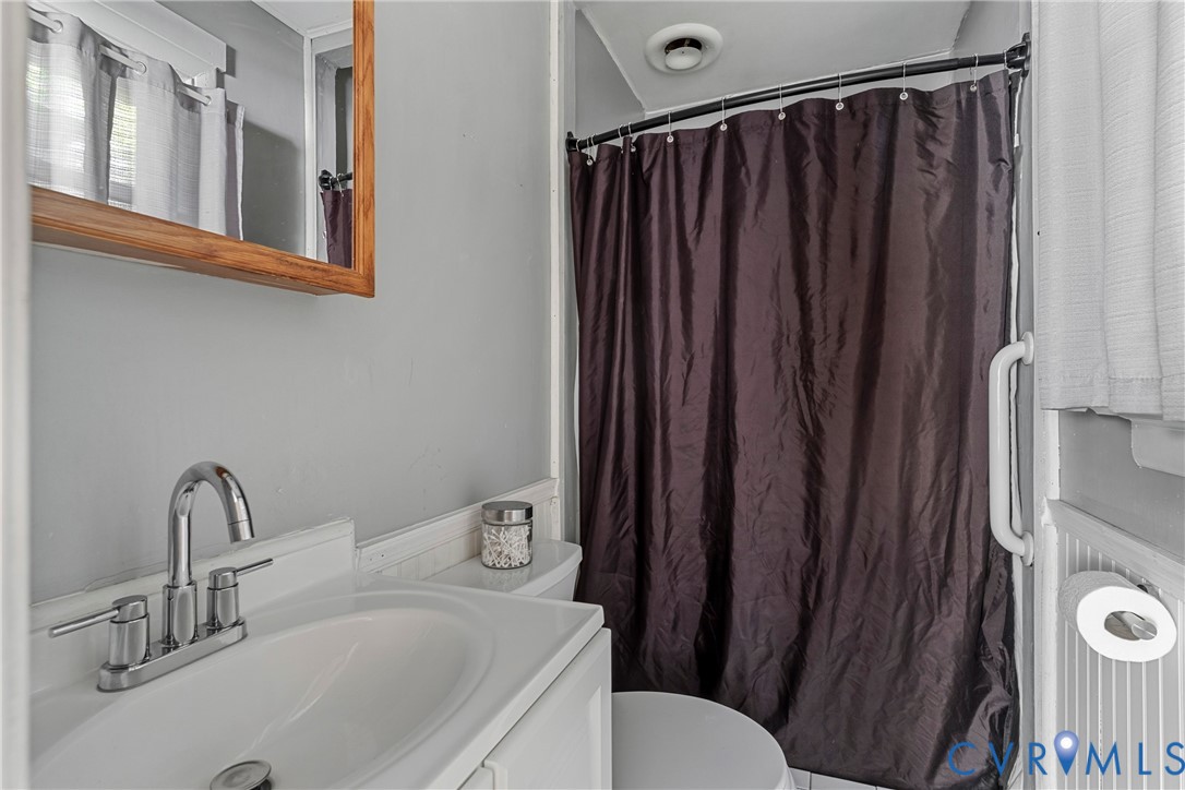 Bathroom featuring a vanity with an integrated basin, a polished chrome high-arc faucet, a wood-framed mirror, and a wall-mounted grab bar