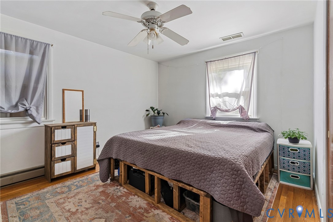 Bedroom featuring wood-finish flooring, white walls, and a ceiling fan with integrated light fixture