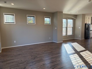 Wood-finish flooring, recessed lighting, and multiple windows featuring neutral wall tones and arched detailing