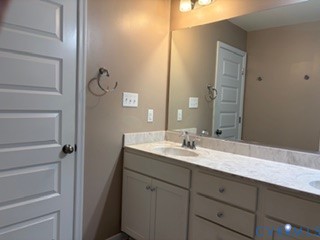 Double vanity with stone-surface countertop, integrated dual sinks, polished chrome fixtures, and a wall-to-wall mirror