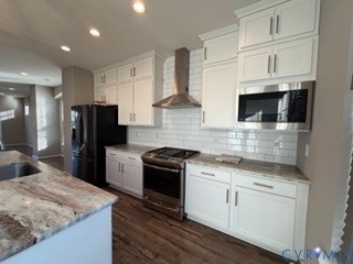 Kitchen featuring shaker-style white cabinetry, stone-finish countertops, stainless steel appliances, a tile backsplash, and wood-finish flooring
